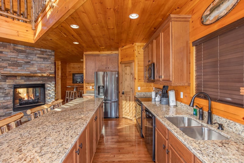 Doublesided fireplace shared with the living room in the kitchen at Four Seasons Palace, a 5bedroom cabin rental located in Pigeon Forge