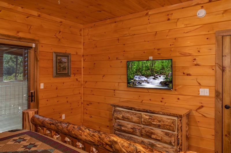 A bedroom with dresser, TV, and deck access at Four Seasons Palace, a 5bedroom cabin rental located in Pigeon Forge