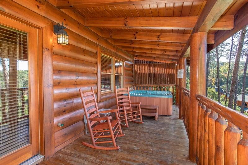 Rocking chairs and hot tub with a privacy fence on a covered deck at Bears Eye View, a 2bedroom cabin rental located in Pigeon Forge