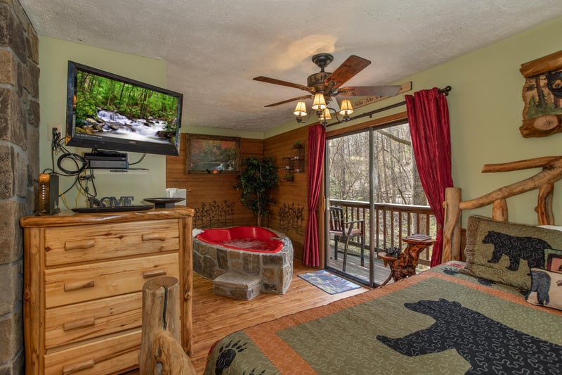 Heart shaped jacuzzi, dresser, and TV in the bedroom at Bear Mountain Hollow, a 1 bedroom cabin rental located in Pigeon Forge