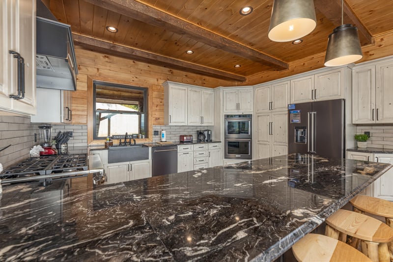 Granite counters, white cabinets, and stainless appliances in the kitchen at Black Bears  Biscuits Lodge, a 6 bedroom cabin rental located in Pigeon Forge