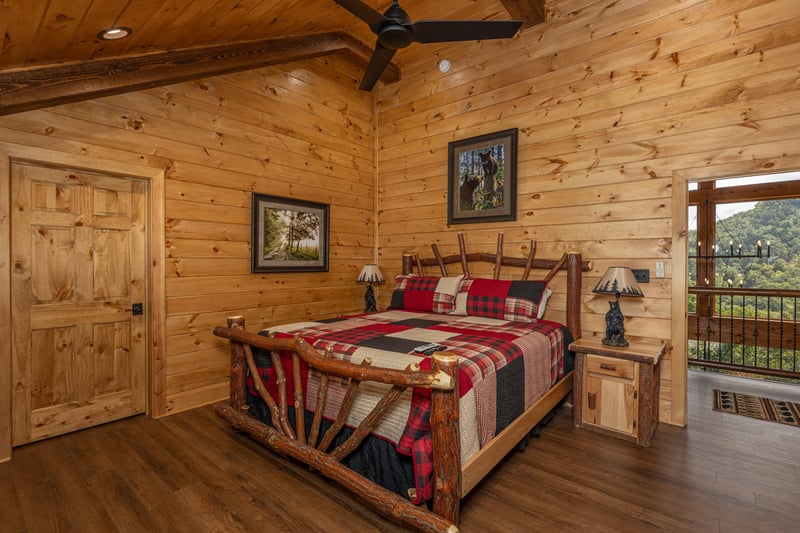 Bedroom with a king log bed, two night stands, and lamps at Black Bears  Biscuits Lodge, a 6 bedroom cabin rental located in Pigeon Forge