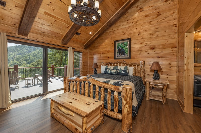 Bedroom with a king log bed, night stands, lamps, bench, and deck access at Black Bears  Biscuits Lodge, a 6 bedroom cabin rental located in Pigeon Forge