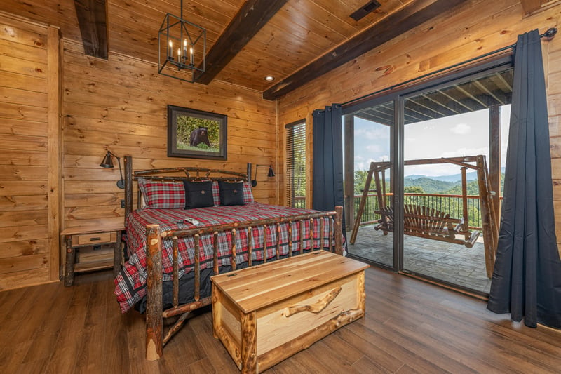 Bedroom with a log bed, night stand, trunk, and deck access at Black Bears  Biscuits Lodge, a 6 bedroom cabin rental located in Pigeon Forge