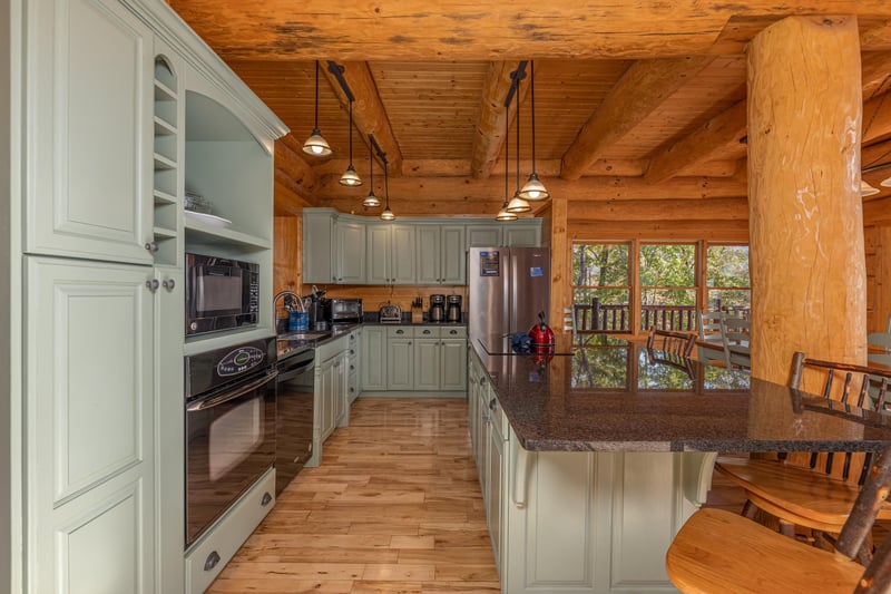 Kitchen with green cabinets and black appliances at Grizzlys Den, a 5 bedroom cabin rental located in Gatlinburg