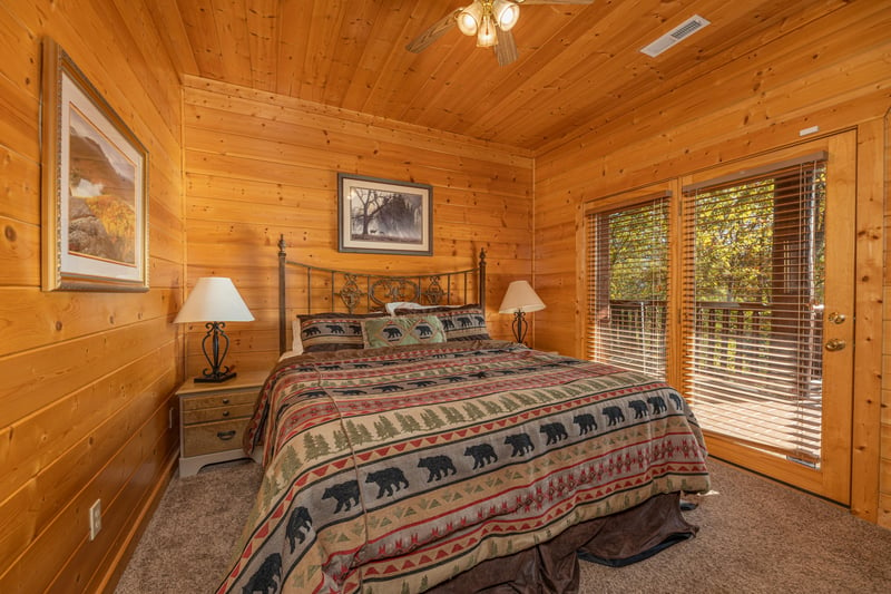 Bedroom with queen bed, two night stands, and deck access at Grizzlys Den, a 5 bedroom cabin rental located in Gatlinburg