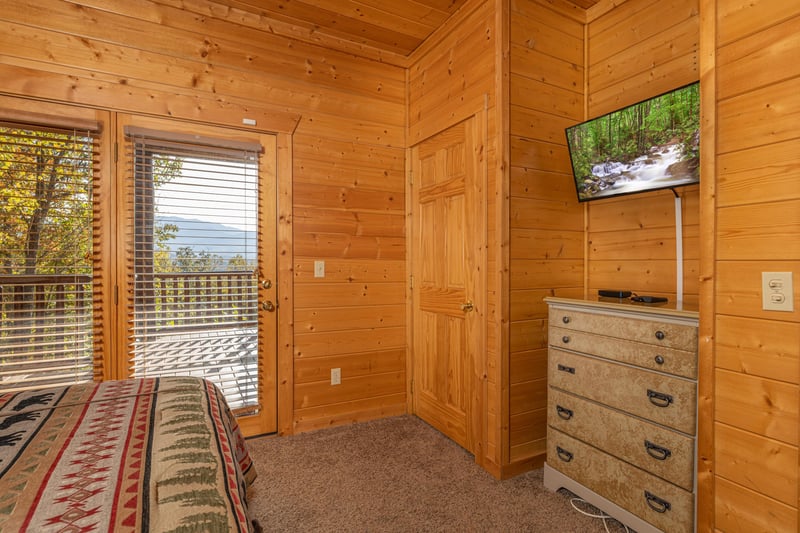 Dresser, TV, and deck access in a bedroom at Grizzlys Den, a 5 bedroom cabin rental located in Gatlinburg