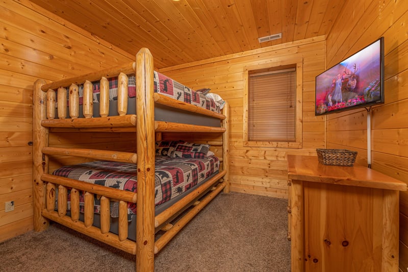 Bunk beds, dresser, and TV in a bedroom at Grizzlys Den, a 5 bedroom cabin rental located in Gatlinburg